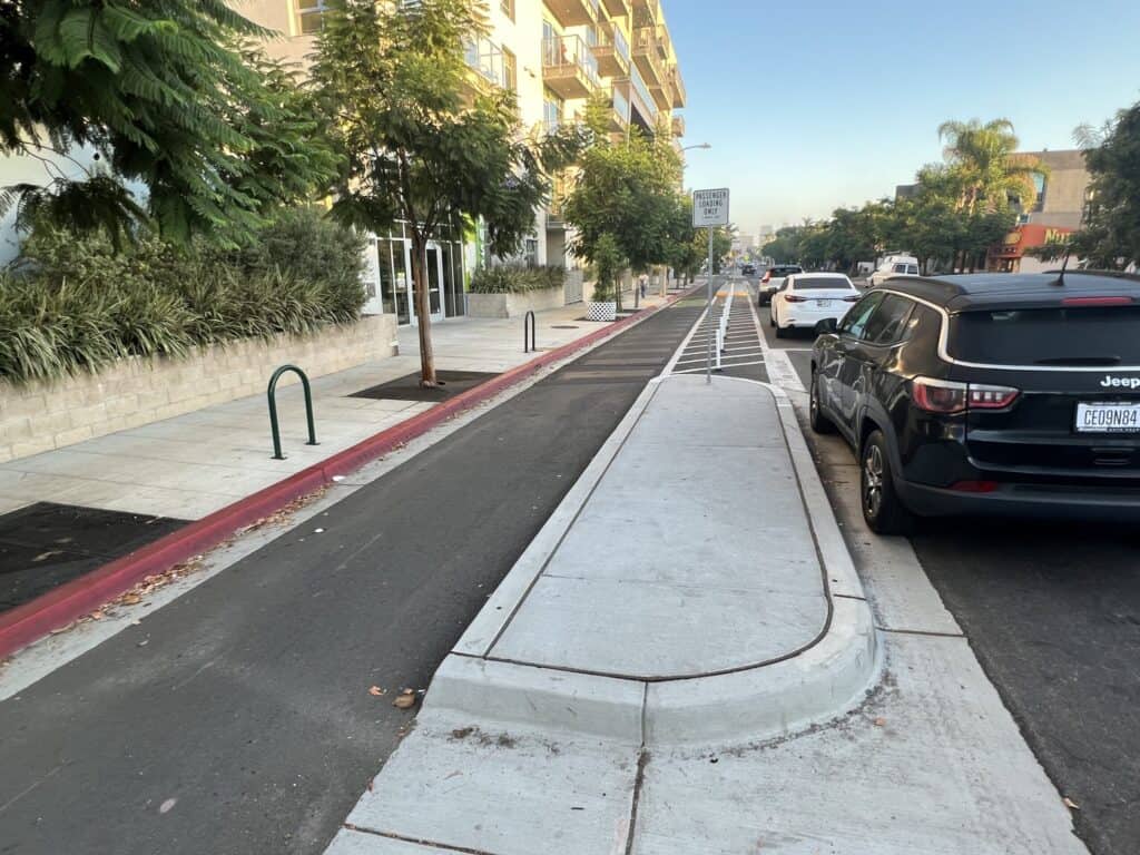 Bike lane separated from street by concrete sidewalk median.