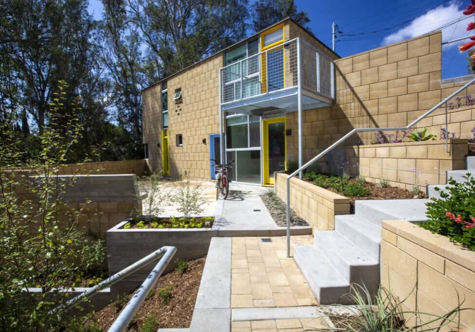 The outside of a modern brick home, nestled in the trees on the edge of a canyon.