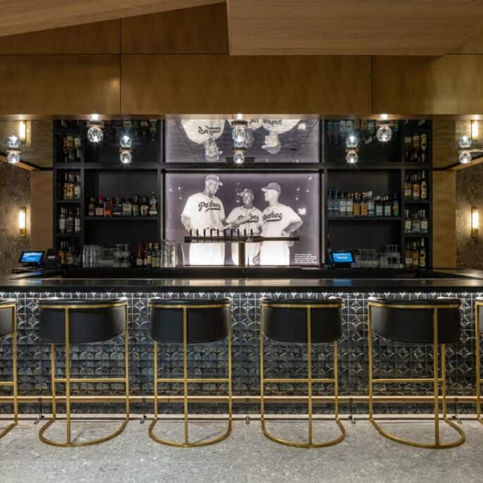 CJ Petco Park Blue Shield Home Plate Club features a wood-panel bar designed in a mid-century modern aesthetic with vintage baseball photographs on the walls.