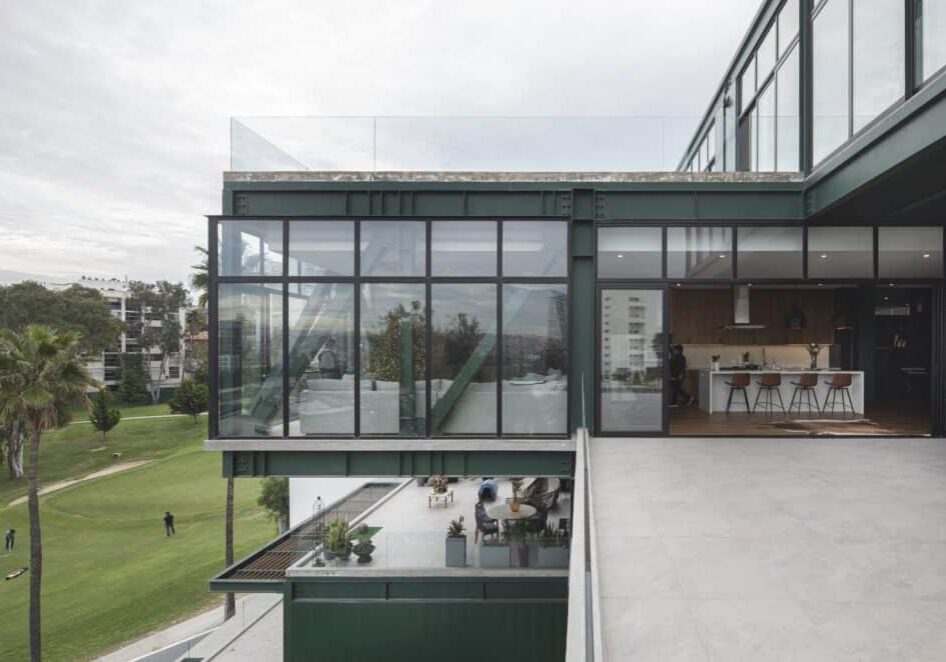 The outside of a modern residential building with large, glass windows that open to the outdoors.