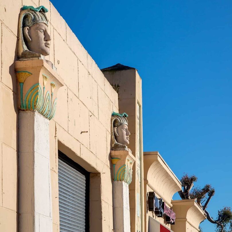 Close up of the Egyptian Garage building in City Heights featuring tan stone and busts made to resemble those from ancient Egypt.