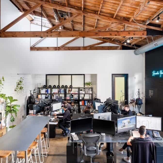 The interior of the GTC Design Studio features a communal work space with large meeting tables and computer stations.