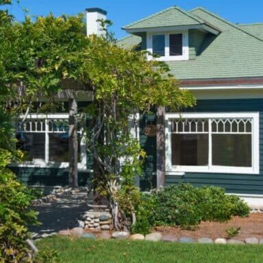 The home of the La Jolla Historical Society is a dark green craftsman bungalow set against lush greenery.