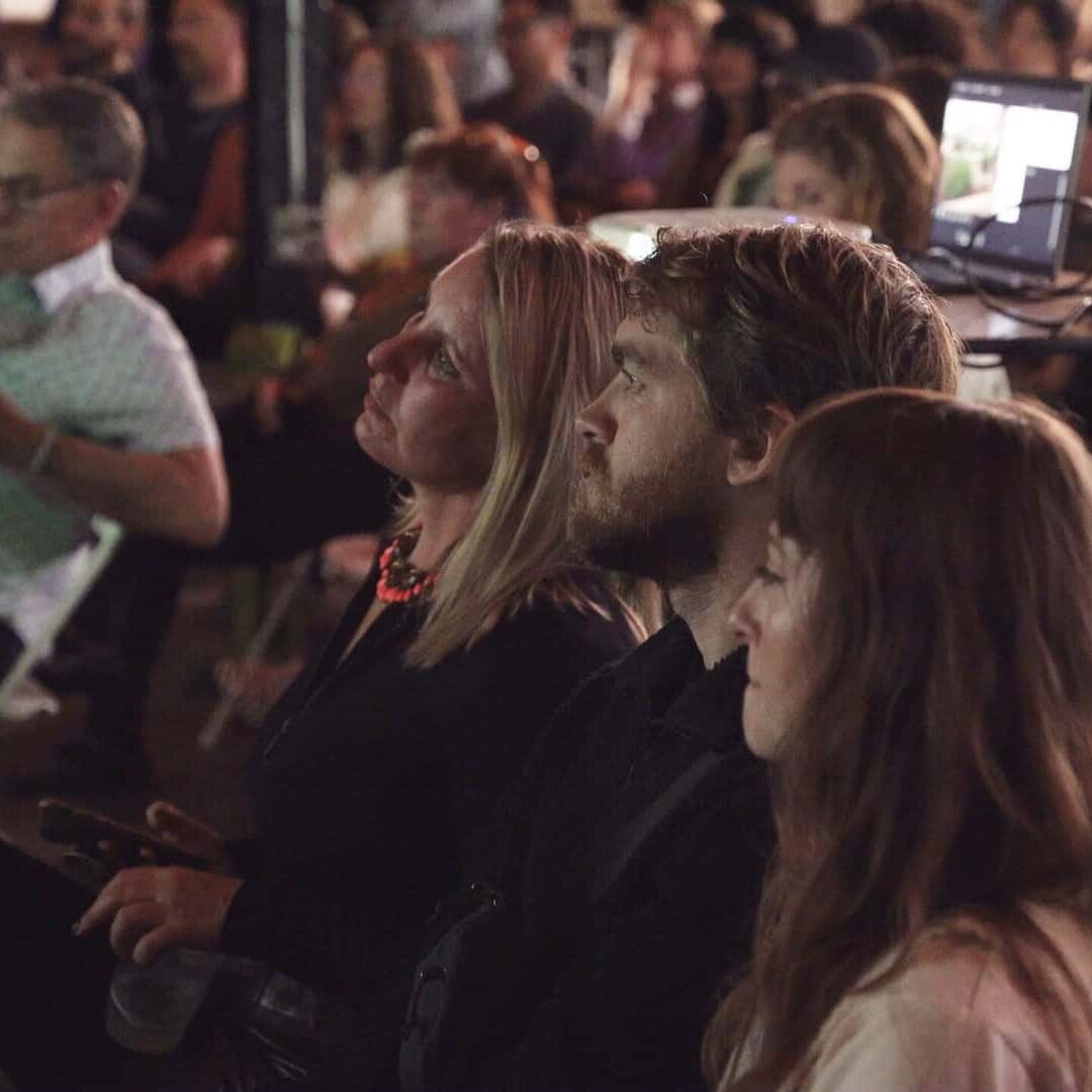 A group of people sit in the audience during a PechaKucha Night event