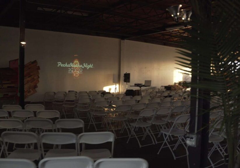 A screen that reads "PechaKucha Night 20x20" and seating area prior to the start of the event
