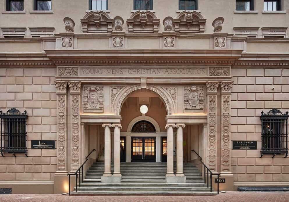 Front facade of historic building in downtown San Diego featuring Roman-style columns, engraved stone, and architectural details.