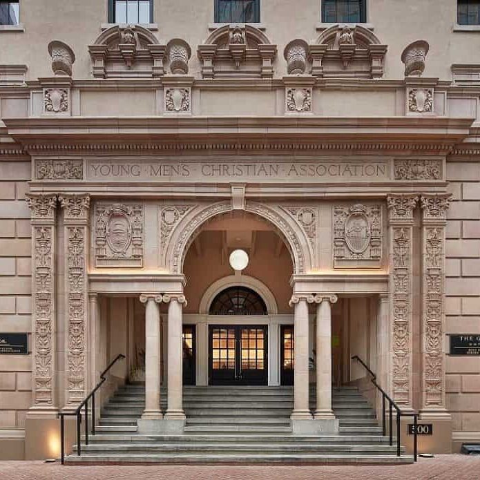 Front facade of historic building in downtown San Diego featuring Roman-style columns, engraved stone, and architectural details.