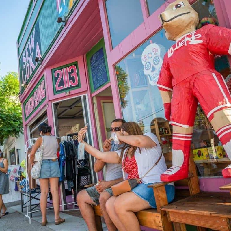 A couple sit on a bench outside of a storefront on Logan Avenue.