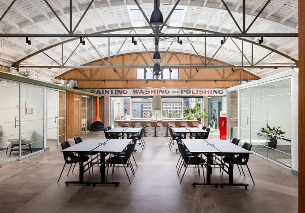 Interior of a modern, collaborative workspace with large work tables and bright lighting.